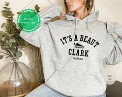 a woman wearing a gray hoodie that says it&#39;s a beauty clark